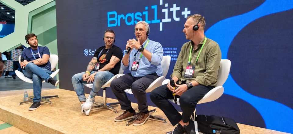 Quatro participantes em um painel de conferência, com microfones e fones de ouvido.